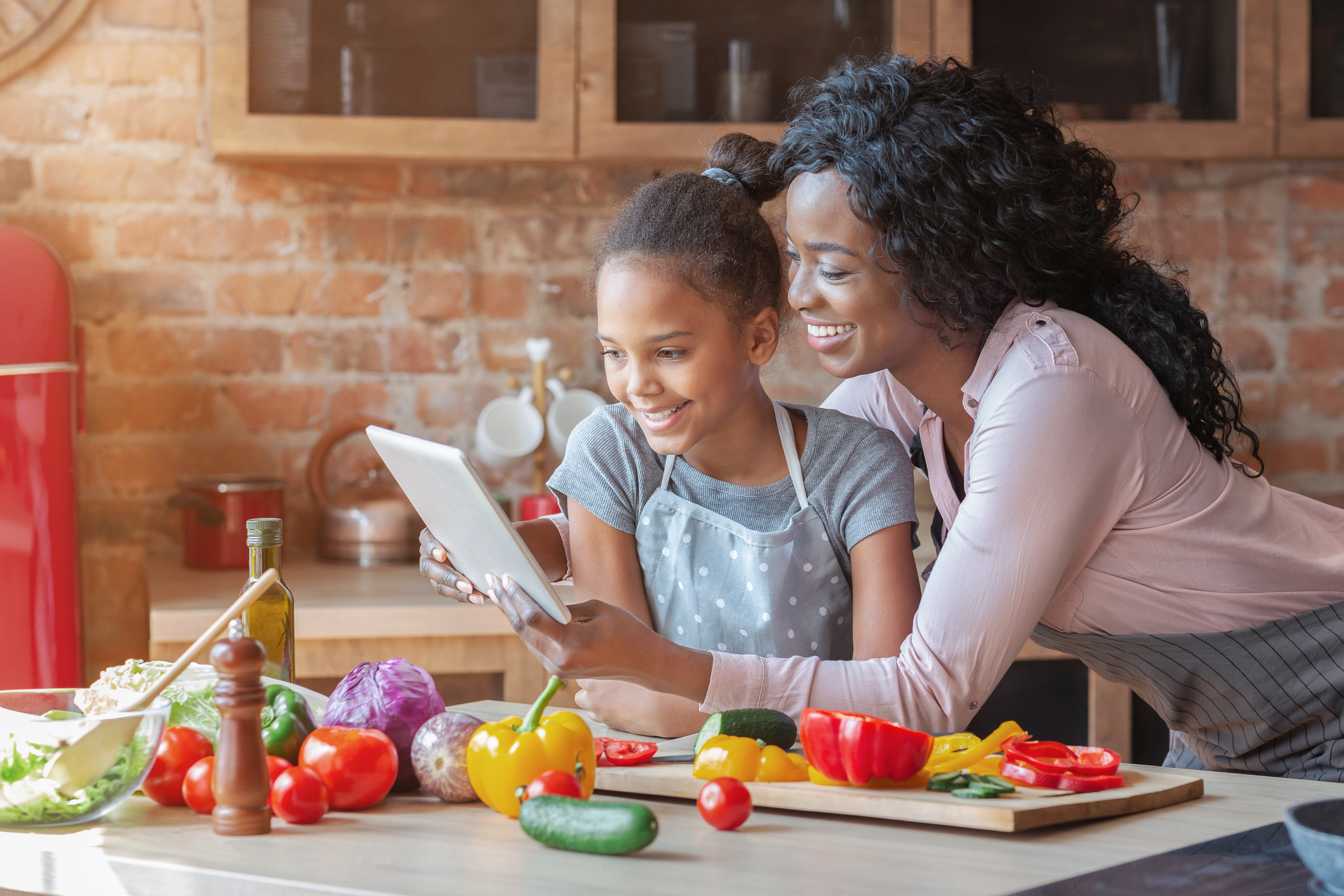 Mommy and daughter reading recipe on tablet at kitchen