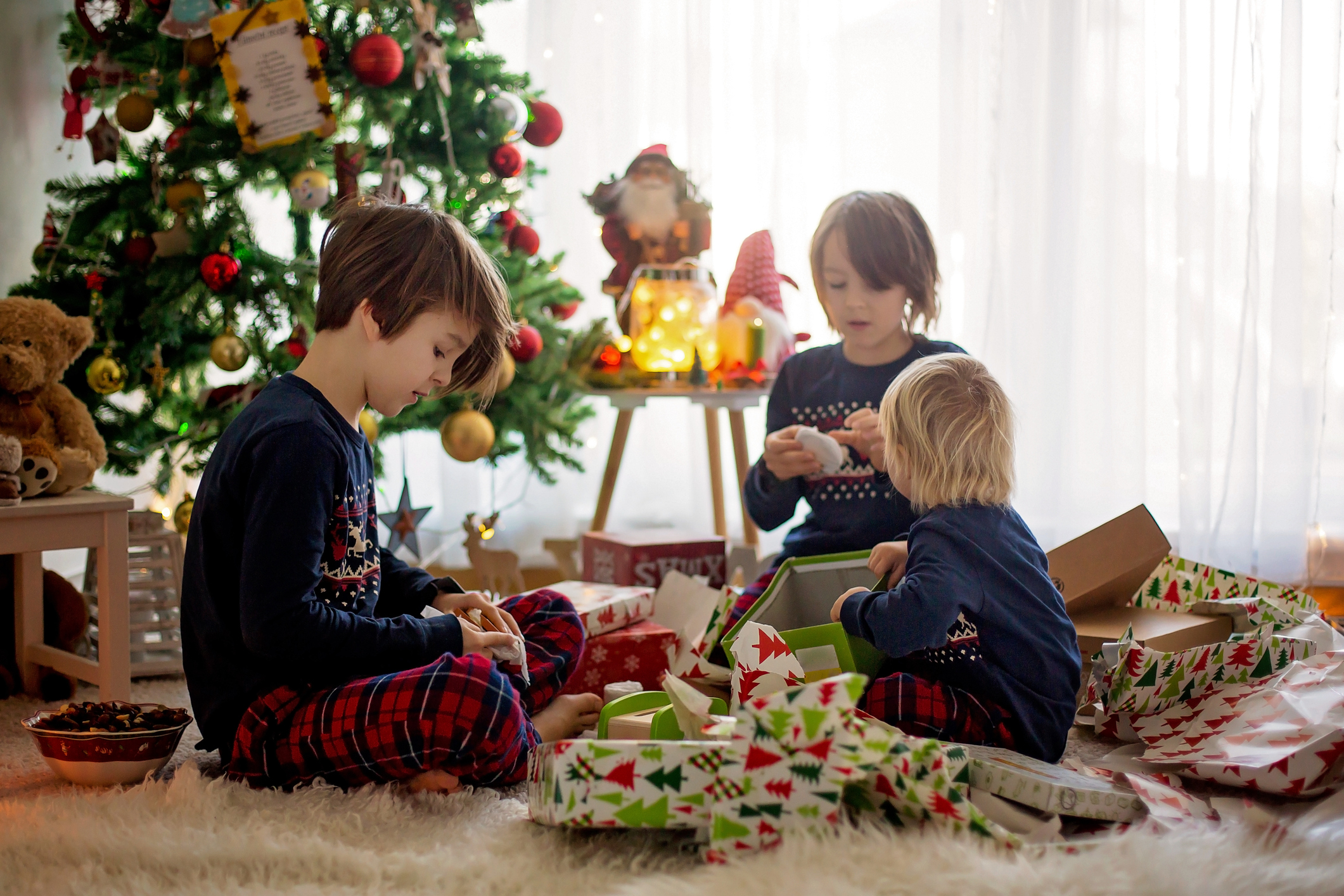 Happy children, boys, opening presents on christmas day, dressed in pajamas