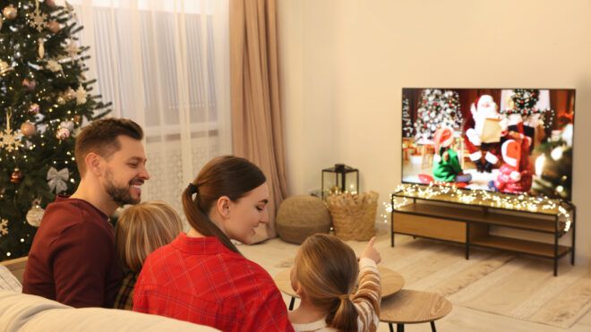 Happy family spending time together near TV in cosy room. Christmas atmosphere