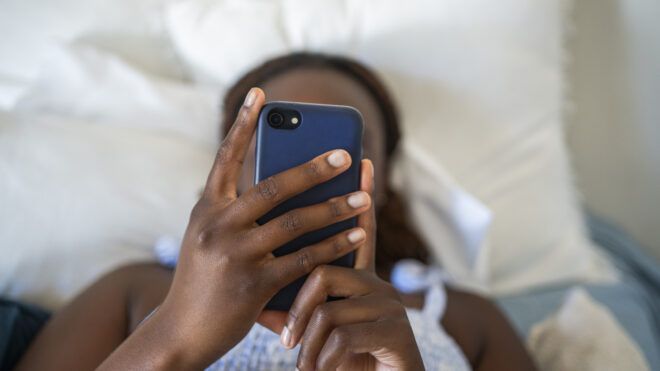 Teenage girl using a phone while lying on her bed