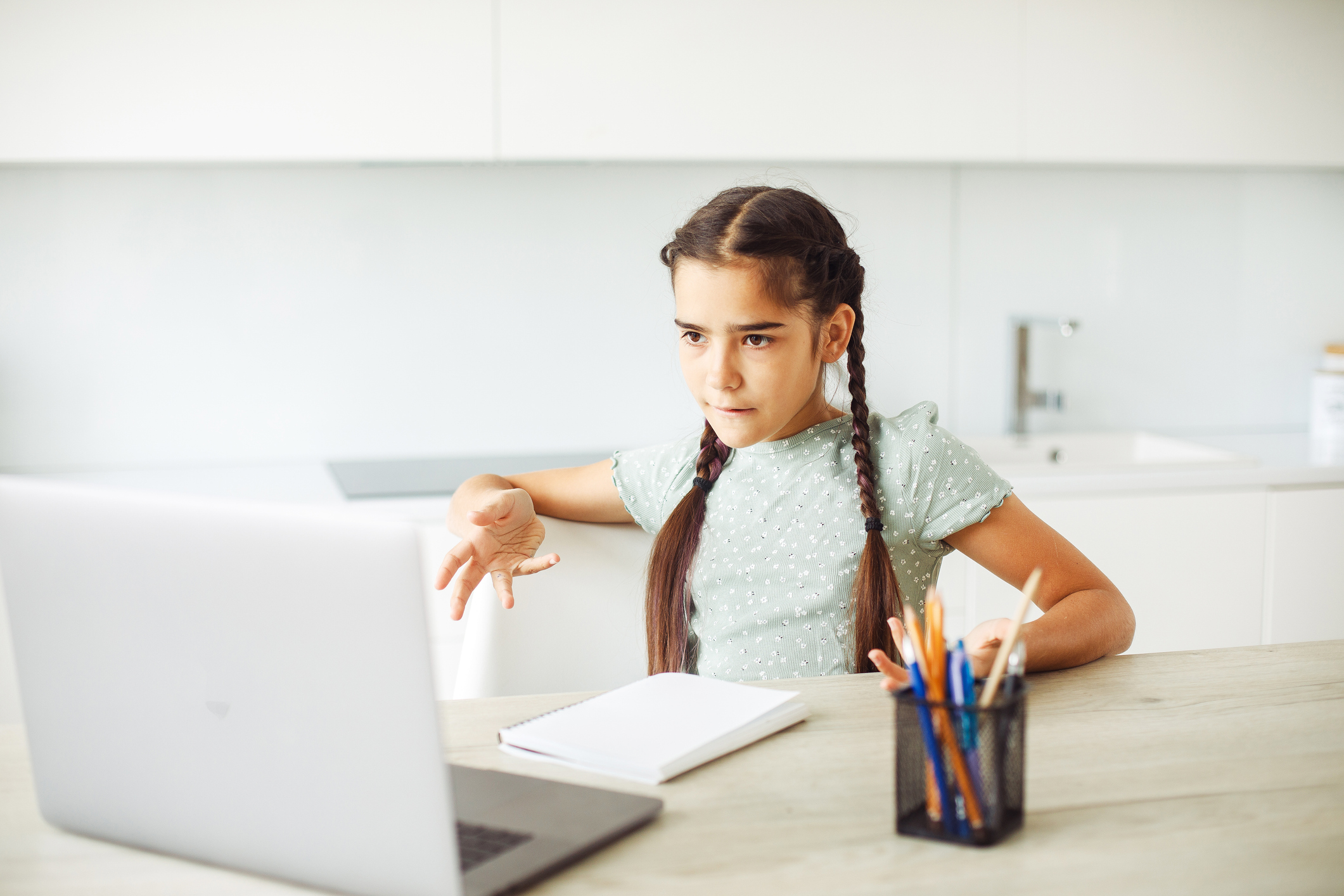 Schoolgirl sitting at home at laptop and doing homework