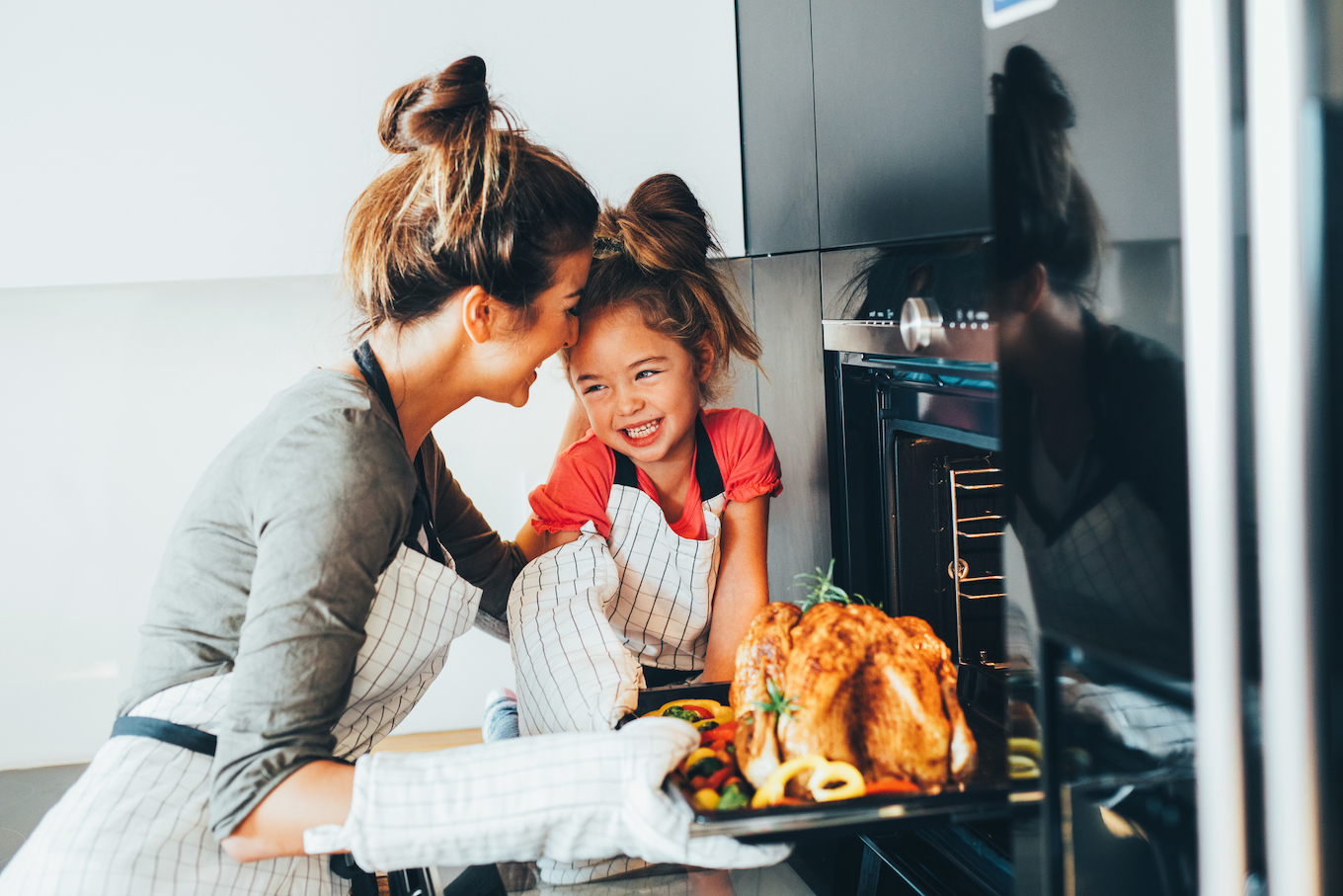 Mom and daughter taking turkey out of the oven