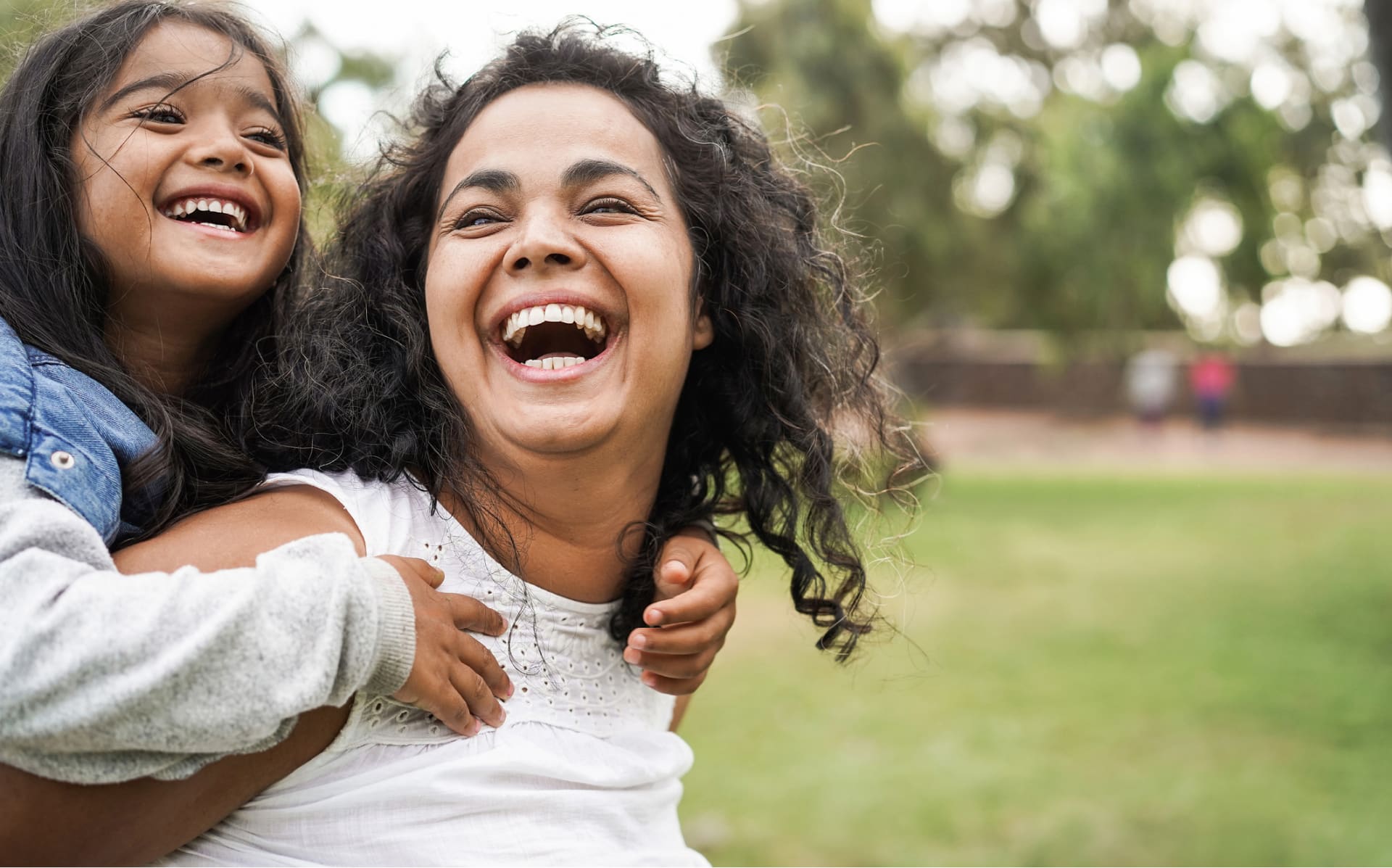 Smiling mom with daughter hanging on her back