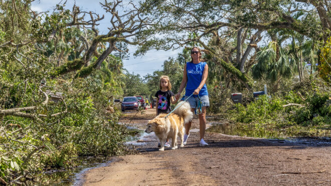 Olivia Chasse with her daughter Charlotte, walk their golden retriever Ben down Dahlia Lane in Vero Beach, Florida, Saturday, Oct. 12, 2024. Ben is a retired therapy dog, and the Chasses took him out walk to help cheer people up after tornadoes from Hurricane Milton damaged many Vero Beach homes earlier in the week.