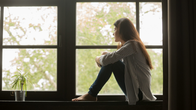 teen girl sitting in large window looking outside